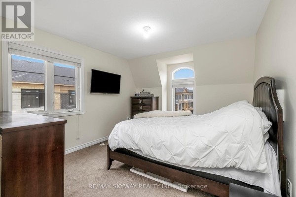 Bedroom with two windows, wall-mounted TV, carpeted floor - 10 - 200 Veterans Drive, Brampton