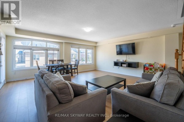 Open concept living room with hardwood floors, wall-mounted TV, dining area - 10 - 200 Veterans Drive, Brampton