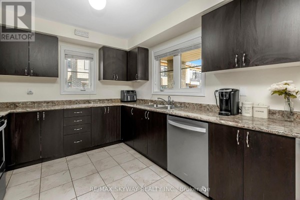 Kitchen with dark cabinets, speckled countertops, tile floors, dishwasher, double sink - 10 - 200 Veterans Drive Brampton