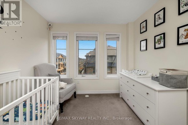 Nursery room with white crib, dresser, three windows, and carpet floors - 10 - 200 Veterans Drive, Brampton