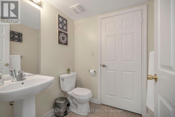 Modern bathroom with pedestal sink, toilet, and tiled floor - 10 - 200 Veterans Drive, Brampton