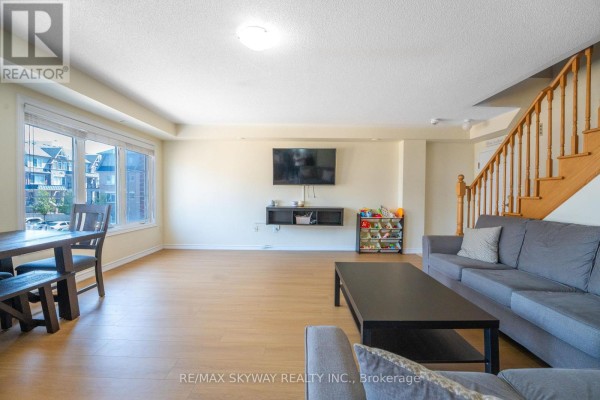 Open concept living room with hardwood floors, large windows, and a staircase - 10 - 200 Veterans Drive, Brampton