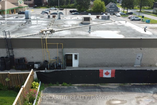 Rear exterior of the commercial building with stacked tires and a Canadian flag. - 10 - 226 First Avenue E, Shelburne
