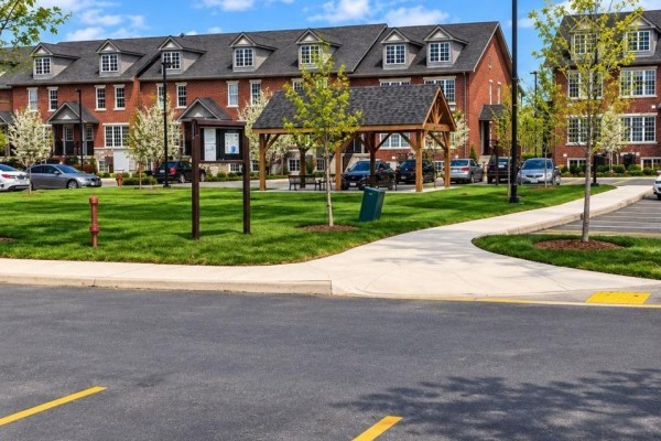 Exterior view of townhouse complex with green space and parking lot. - 10 - 242 Penetanguishene Road, Barrie