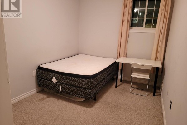 Bedroom with a queen-size mattress, desk, chair, and light beige curtains. - 10 - 242 Penetanguishene Road, Barrie