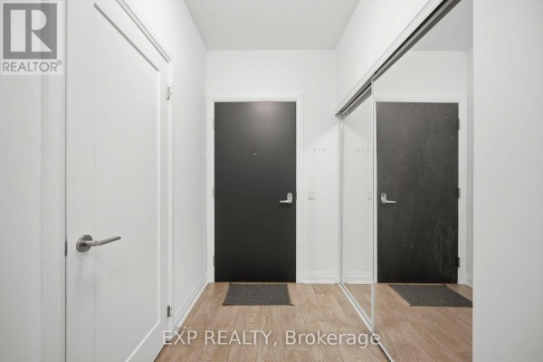 Apartment entryway with white walls, a dark front door, and a floor-to-ceiling mirrored closet. - 10 - 286 Main Street, Toronto