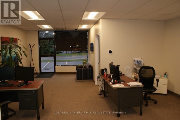 Office interior with multiple desks, chairs, computers, and a large window with blinds. - 10 - 500 Wentworth Street E, Oshawa