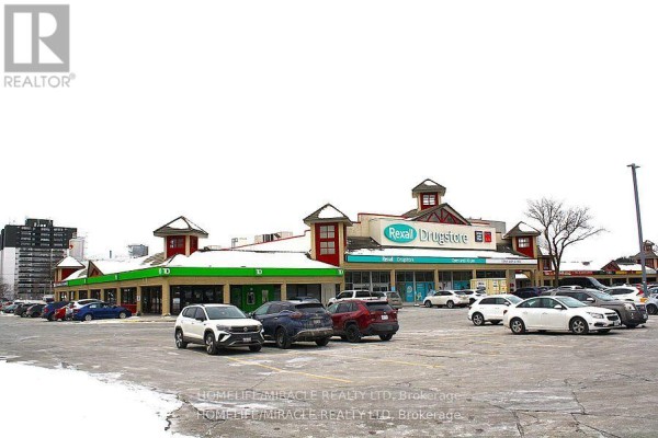 Exterior view of a commercial strip mall with a Rexall Drugstore and other businesses. - 10 - 666 Woolwich Street, Guelph