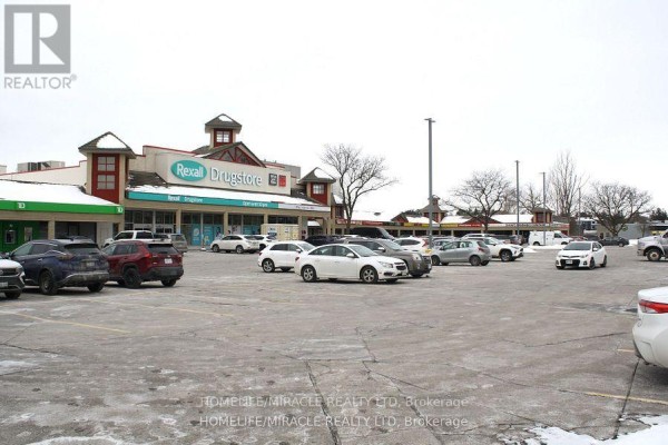 Parking lot in front of a commercial strip mall with snow on the ground. - 10 - 666 Woolwich Street, Guelph