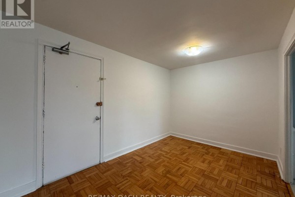 Empty room with parquet flooring, overhead light fixture, and entrance door - 10 - 69 Old Mill Terrace, Toronto