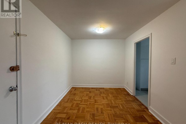 Another view of the empty room with parquet flooring and doorway to adjacent space - 10 - 69 Old Mill Terrace, Toronto
