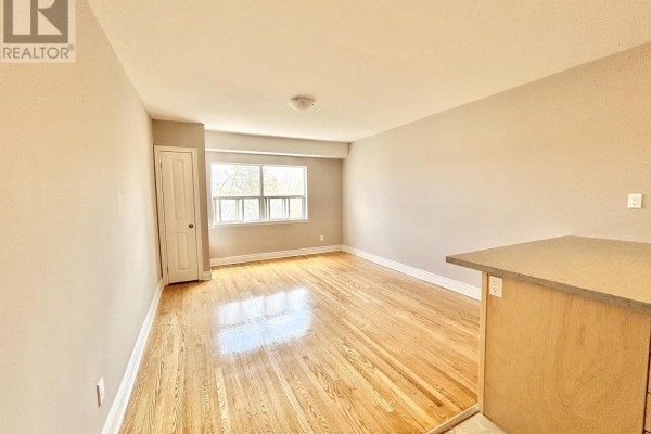 View of the living area and kitchen island, featuring hardwood floors and a window with natural light. - 10 - 80 Twenty Fifth Street, Toronto