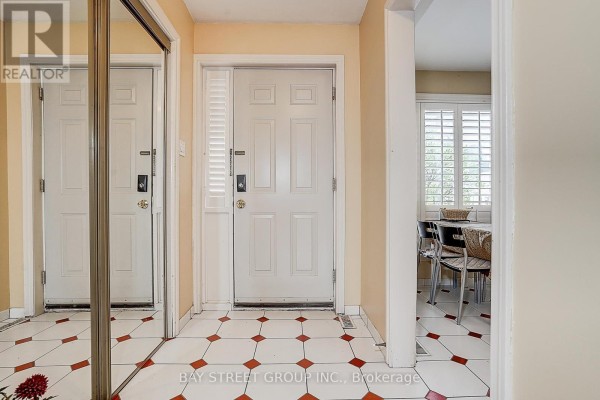 Hallway with yellow walls, checkered tile floor, and doorway leading to a living area. - 10 - 91 Rameau Drive, Toronto