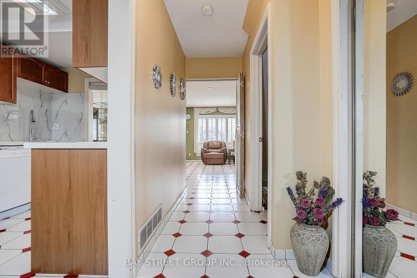 View of a kitchen area with wooden cabinets and a hallway leading to a living room. - 10 - 91 Rameau Drive, Toronto