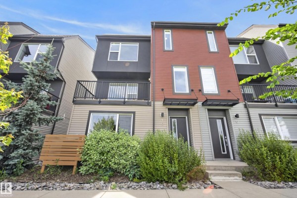 Front exterior of townhouses featuring contrasting siding materials and balconies. - #10 1075 Rosenthal Bv Nw, Edmonton