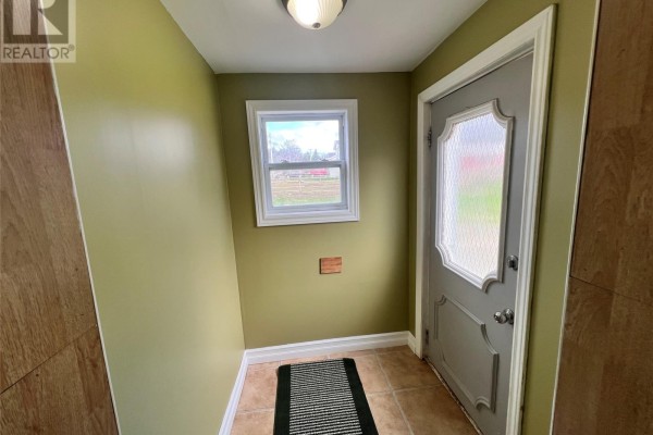 Interior entryway with pale green walls, beige tiled floor, and a grey paneled door. - 10-12 Hill Avenue, Clarkes Beach