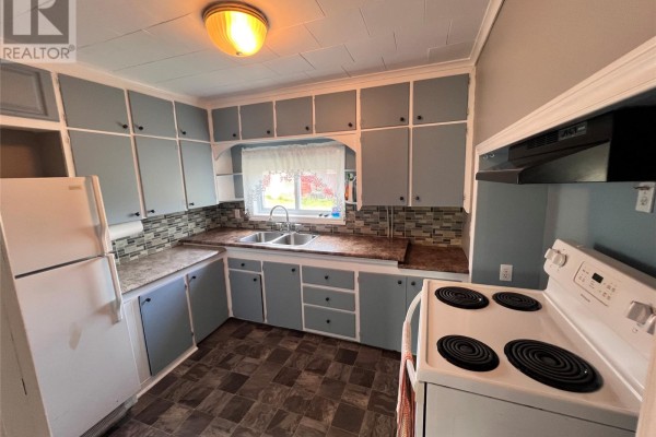 Kitchen with light blue cabinets, white appliances, a double sink, and dark patterned flooring. - 10-12 Hill Avenue, Clarkes Beach