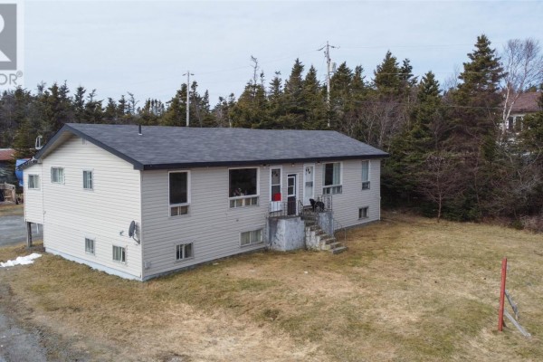 Side view of a beige duplex with multiple windows and a dark roof, surrounded by trees. - 10-14 Effords Sub-division, Bay Roberts