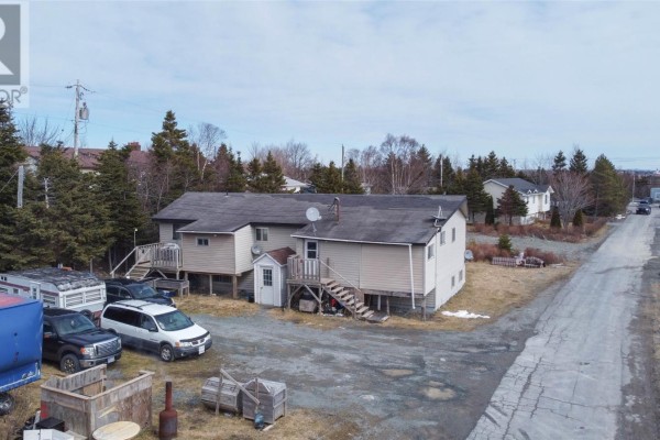 Aerial view of a beige duplex with a gravel driveway and surrounding wooded area. - 10-14 Effords Sub-division, Bay Roberts