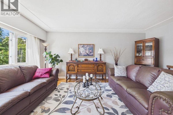 Living room with two brown leather sofas, a patterned rug, and a wooden buffet. - 10 2296 W 39th Avenue, Vancouver