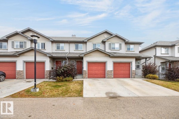 Street view of townhouse complex with parked cars and trees in front. - #10 2816 34 Av Nw Nw, Edmonton