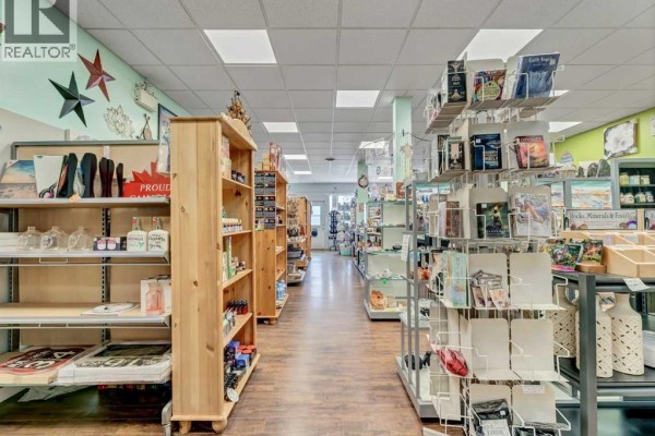 Storefront with large windows displaying merchandise, green door, and promotional signs. - 10 3 Street Se, Redcliff