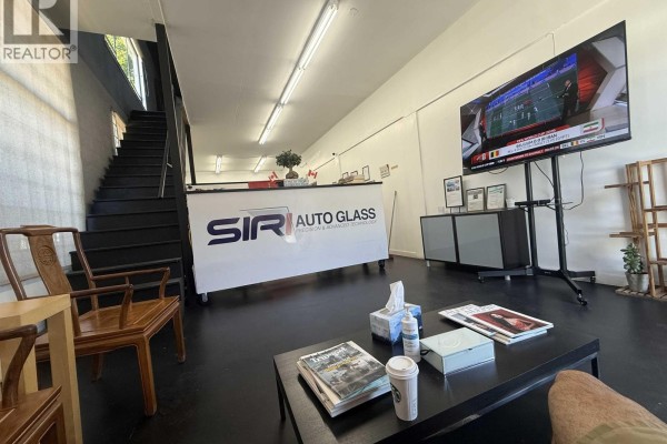Interior waiting area with black floor, chairs, reception desk, and a large television displaying a sports broadcast. - 10 954 Sw Marine Drive, Vancouver