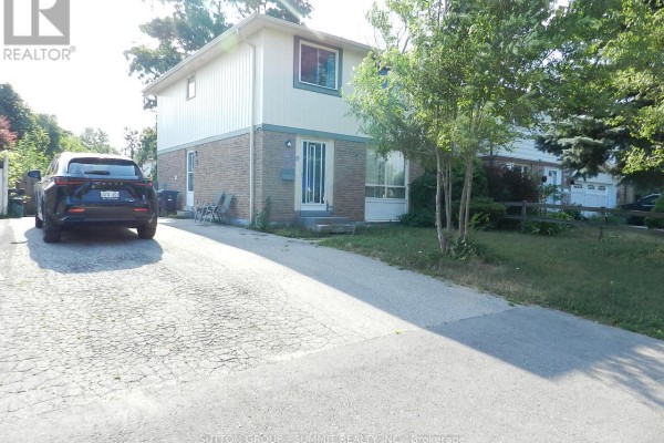 A dark SUV parked on a cracked asphalt driveway next to a house. - 10 Baldoon Road, Toronto