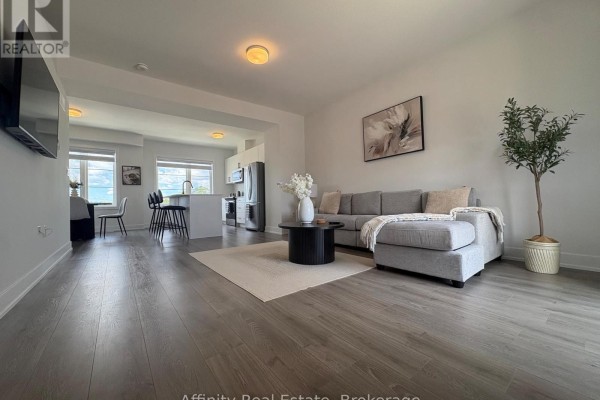 Modern kitchen with white cabinets, stainless steel appliances, and an island with bar stools. - 10 Balladry Boulevard, Stratford