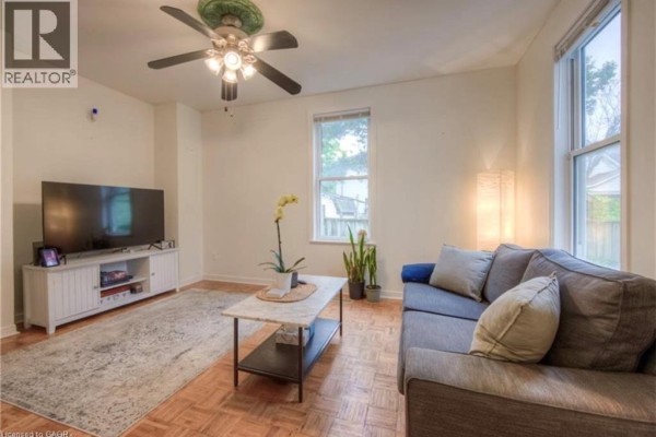 Living room with a gray sofa, marble-topped coffee table, and entertainment unit with a television. - 10 Bruce Street, Brantford