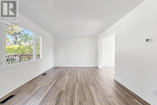 Bright living room with white walls, wide plank flooring, and a doorway to another room. - 10 Buce Avenue, Bradford West Gwillimbury