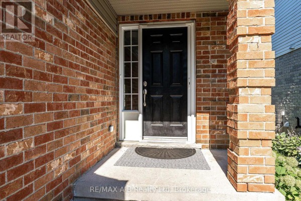 Black front door with glass sidelights and a gray doormat on a concrete porch. - 10 Buckingham Drive, Stratford