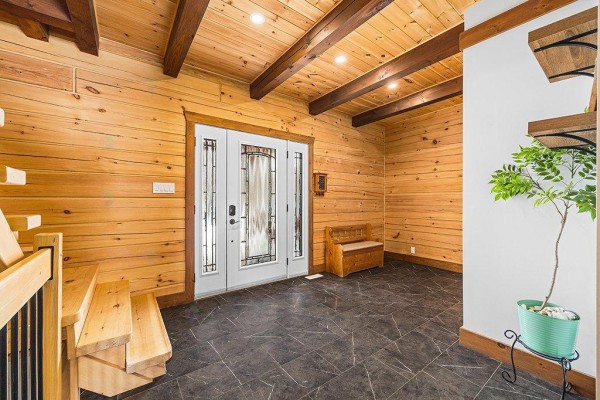 Exterior view of a snow-covered log cabin with a covered porch and outdoor seating. - 10 Ch. Des Outaouais, L Ile Du Grand Calumet