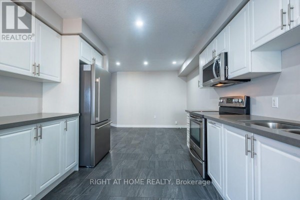 Modern kitchen with white cabinetry, stainless steel appliances, grey countertops, and view to the backyard. - 10 Cittadella Boulevard, Hamilton