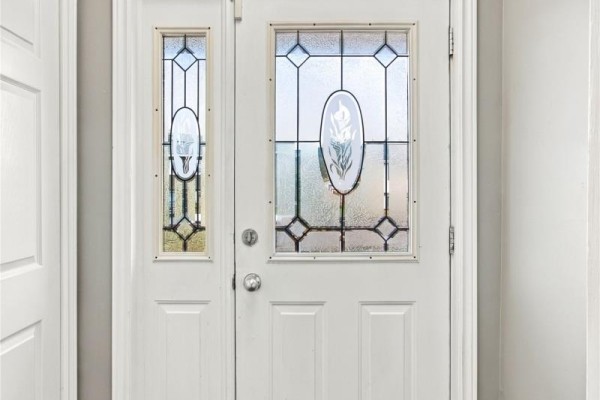 Close-up of a white front door with a decorative glass window pane. - 10 Clevedon Crescent, Paradise