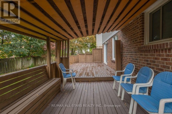 Covered wooden deck with blue chairs, a wooden bench, and a wooden railing overlooking a backyard. - 10 Colette Drive, Whitby