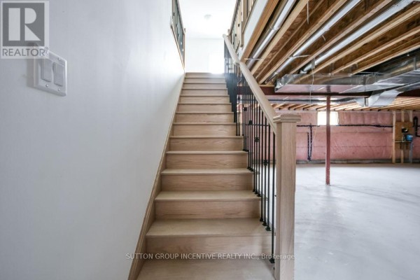 Wooden staircase with black railings leading down to an unfinished basement. - 10 Cottonwood Street, Springwater