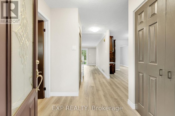 Interior hallway with light wood-look flooring and closet doors. - 10 Donegel Place, Hamilton