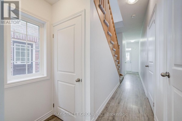 Hallway with laminate flooring, carpeted stairs, and interior doors - 10 Elsegood Drive Guelph