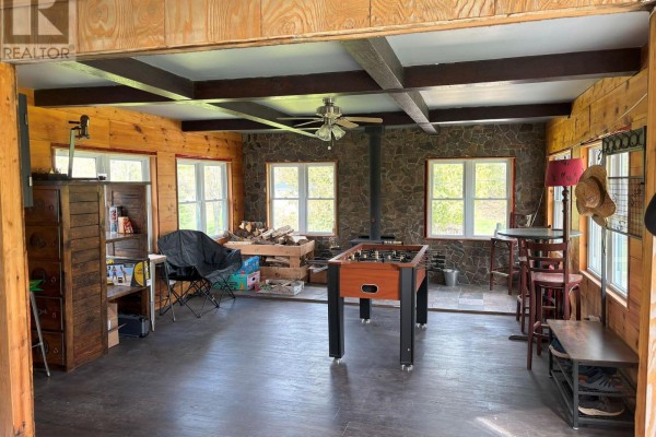 Spacious rec room with foosball table, stone accent wall, wood stove, and windows. - 10 Fire Route 19 Route, Havelock Belmont Methuen