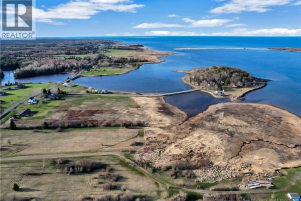 Aerial view of undeveloped land with marshland, water, and houses in the distance. - 10 Florina Street, Cocagne