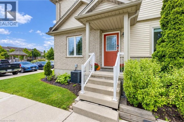 Close-up of the townhouse entrance with concrete steps and a red door. - 10 Foxglove Crescent Unit# 40, Kitchener