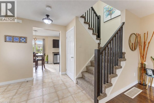 Interior view of a hallway with a carpeted staircase, beige walls, and tile floor. - 10 Foxglove Crescent Unit# 40, Kitchener