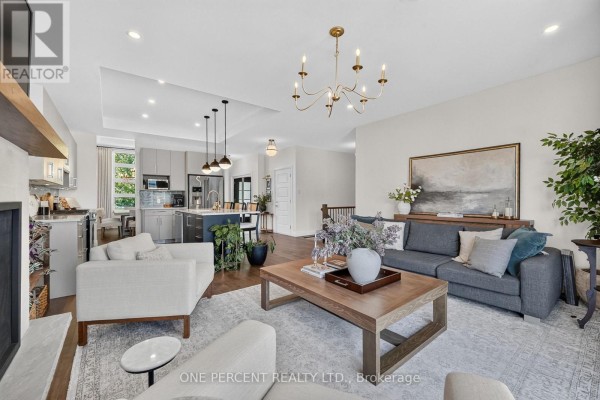 Modern living room with fireplace, sofa, and open-concept kitchen with island - 10 Granite Street Clarence Rockland