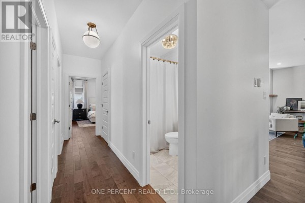 Hallway with hardwood floors, modern lights, and doorways to bathroom & bedroom - 10 Granite Street Clarence Rockland