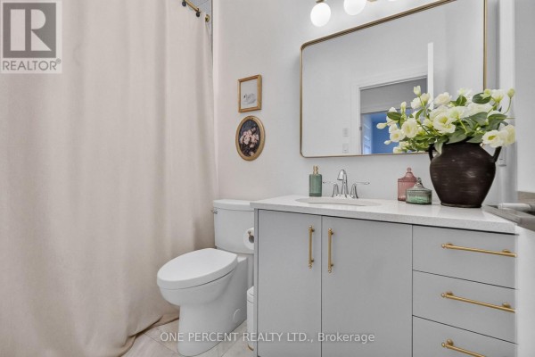 Modern bathroom with grey vanity, gold hardware, large mirror, and floral decor - 10 Granite Street Clarence Rockland