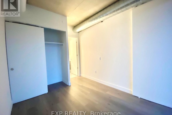 Bedroom with sliding closet doors and view into hallway and bathroom. - 10 James #417 Street, Ottawa