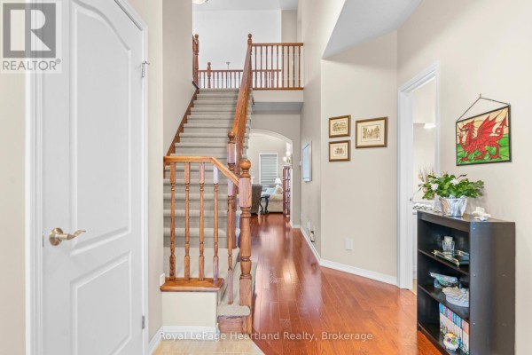 Wooden dining table with chairs next to an arched doorway and kitchen view. - 10 Macpherson Avenue, Huron East