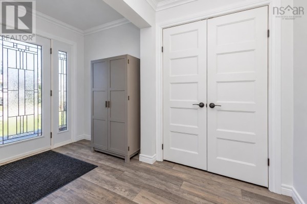 Interior entryway view showing a grey cabinet with hanging coats and double white doors with panel detailing. - 10 Melissa Crescent, Sydney