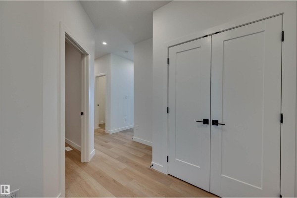 Hallway with light wood floors, white walls, and multiple white doors.  - 10 Owl Ridge Cl, Fort Saskatchewan